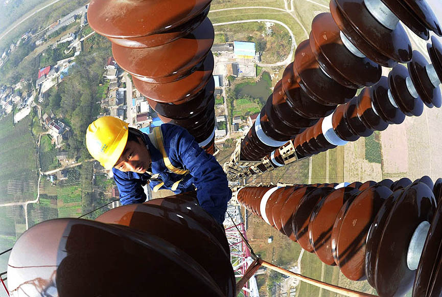 Un trabajador revisando un poste de electricidad en Anqing, provincia de Anhui, China. China Daily. Reuters