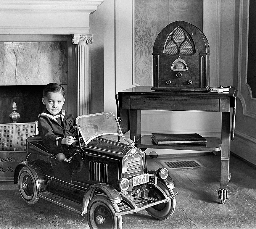 Sentado en su automóvil de juguete, junto a una radio Atwater Kent, 1931. Shorpy