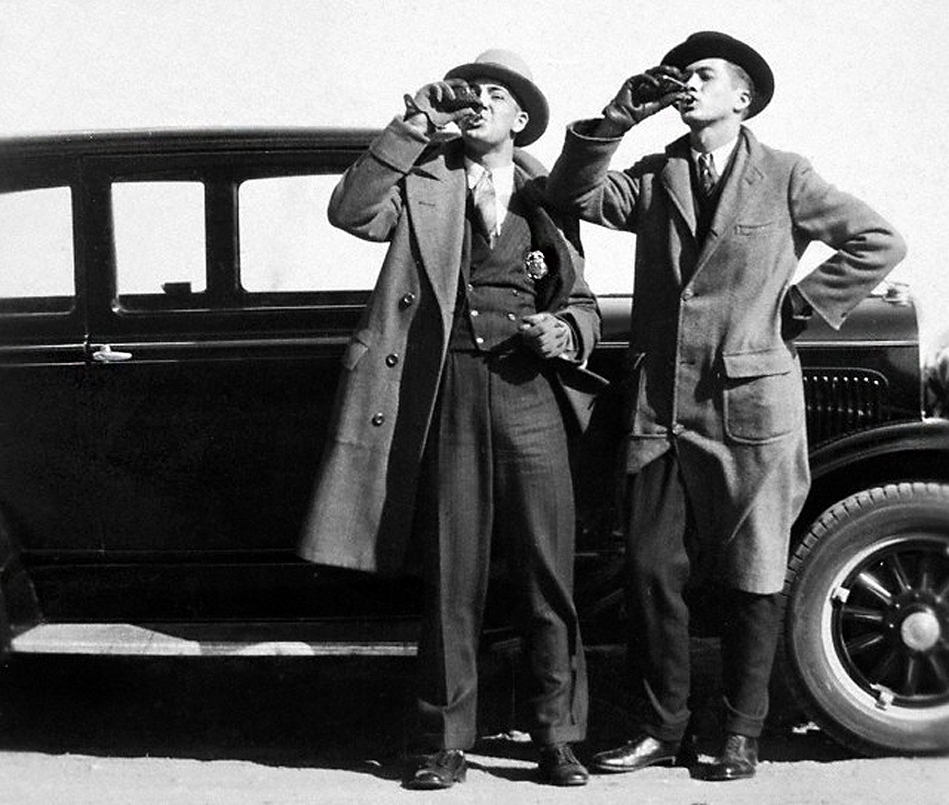 Oficial de policía bebiendo de una petaca con su acompañante. 1930. Corbis