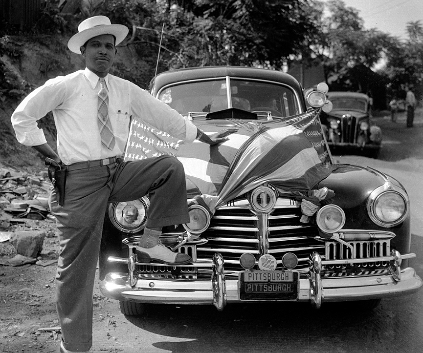El comisario de policía Juan Buddlee posando frente a un Pontiac, 1945. Charles Harris