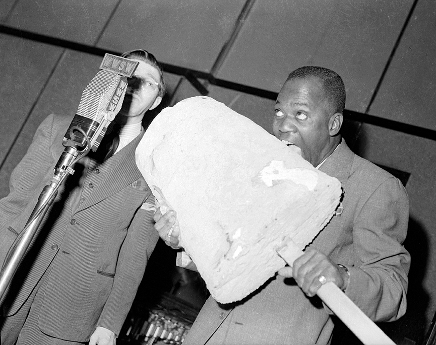 Bill Robinson fingiendo comer un enorme polo de crema ante la sorprendida mirada de un locutor de radio, en 1941. Charles Harris