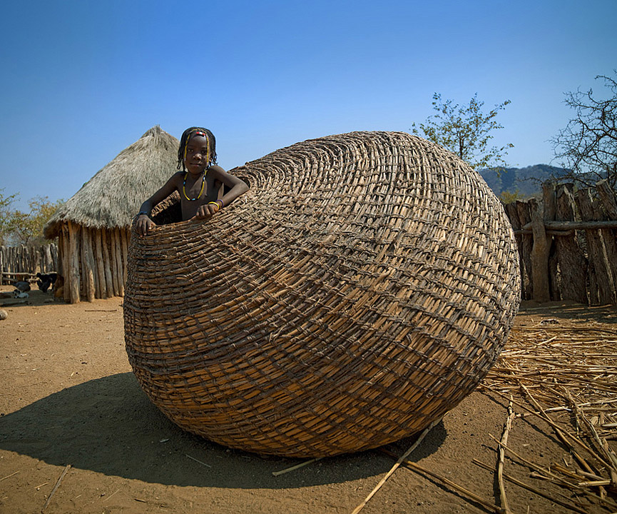 Niña de la tribu Mundimba en el interior de una gigantesca cesta, Angola. Eric Lafforgue